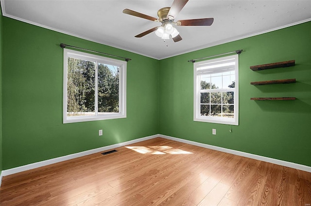 unfurnished room featuring a healthy amount of sunlight, light hardwood / wood-style floors, ornamental molding, and ceiling fan