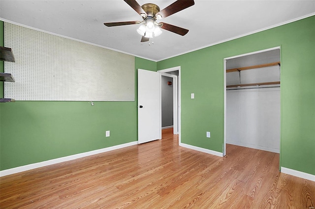 unfurnished bedroom with a closet, light wood-type flooring, ceiling fan, and crown molding