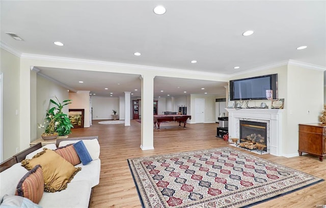 living room featuring light wood-type flooring, pool table, ornamental molding, and a high end fireplace