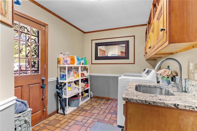 laundry area featuring washer and clothes dryer, ornamental molding, sink, and cabinets