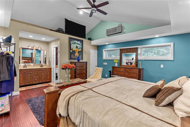 bedroom featuring a wall unit AC, dark wood-type flooring, vaulted ceiling, ensuite bath, and ceiling fan