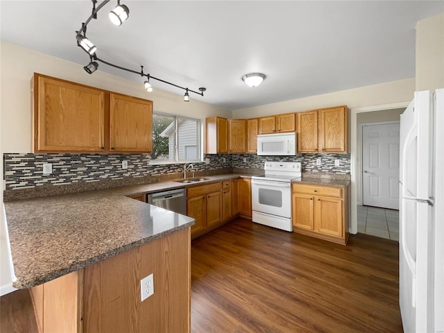 kitchen featuring dark wood-type flooring, tasteful backsplash, white appliances, kitchen peninsula, and sink