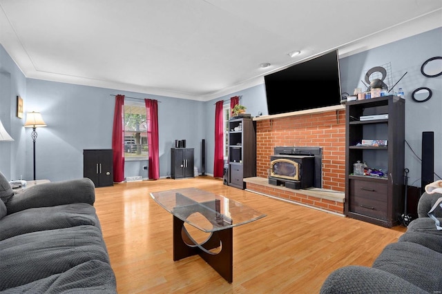 living room with ornamental molding, a fireplace, hardwood / wood-style floors, and a wood stove