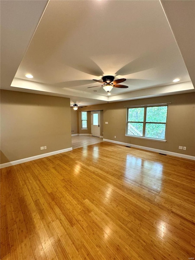 spare room with ceiling fan, light hardwood / wood-style flooring, and a tray ceiling