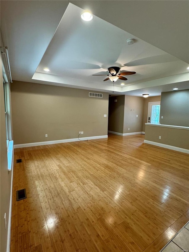 unfurnished room featuring light hardwood / wood-style floors, ceiling fan, and a tray ceiling