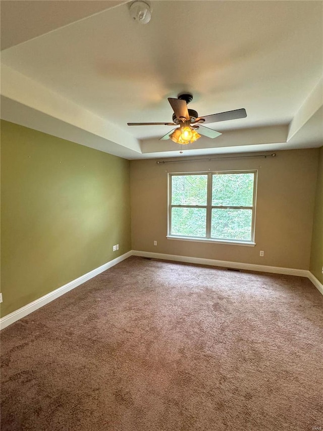 unfurnished room featuring ceiling fan, carpet floors, and a tray ceiling