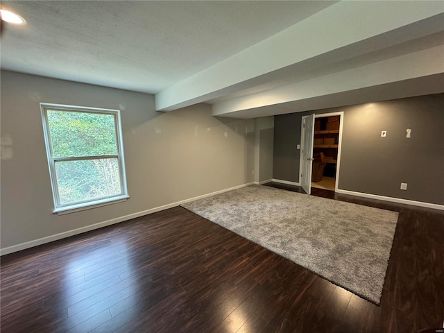 basement featuring a textured ceiling and dark hardwood / wood-style floors