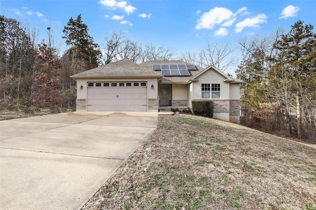 ranch-style home featuring a garage, concrete driveway, brick siding, and solar panels