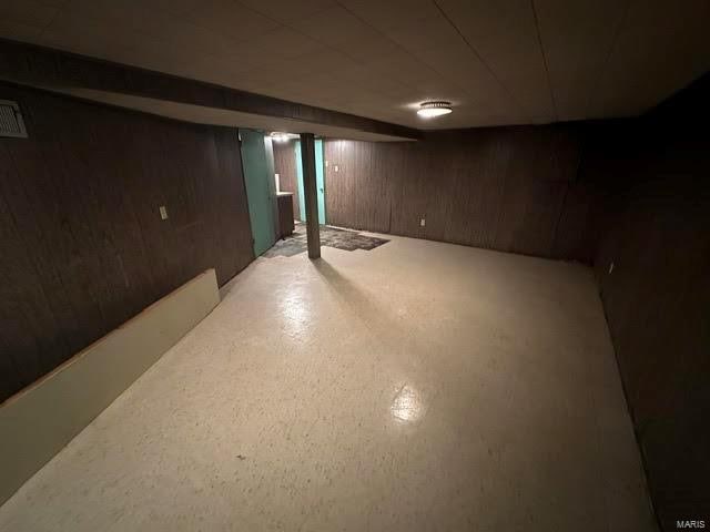 basement featuring wooden walls