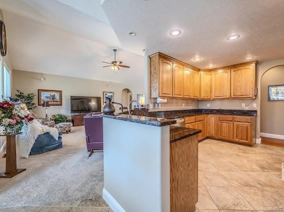 kitchen with ceiling fan, light colored carpet, a textured ceiling, and kitchen peninsula