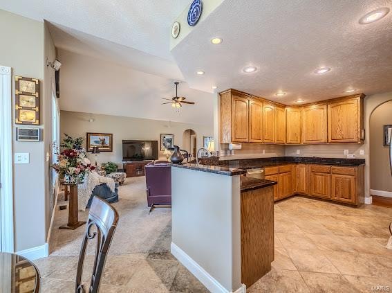 kitchen featuring vaulted ceiling, kitchen peninsula, ceiling fan, and a textured ceiling