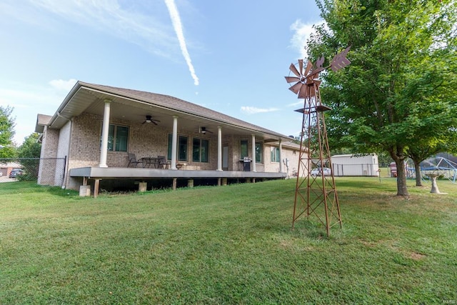 rear view of property featuring ceiling fan and a yard