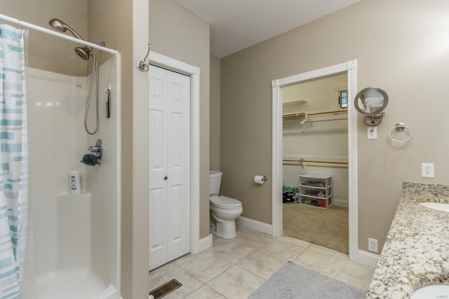 bathroom featuring walk in shower, vanity, toilet, and tile patterned floors