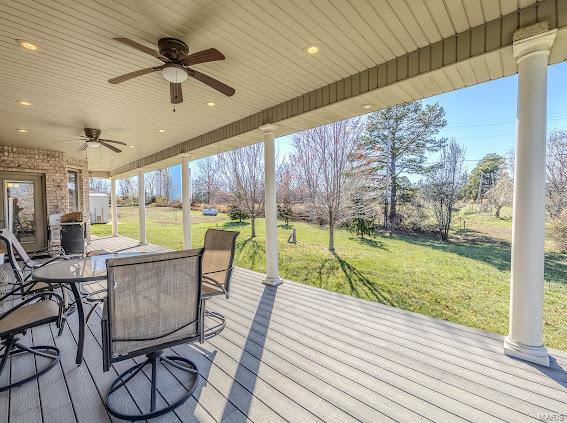 wooden terrace featuring ceiling fan and a yard