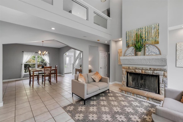 tiled living room with a fireplace, a high ceiling, and a notable chandelier