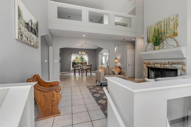 tiled living room featuring a chandelier, a fireplace, and a high ceiling