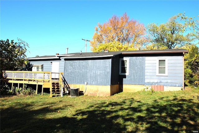 back of property with a wooden deck and a lawn