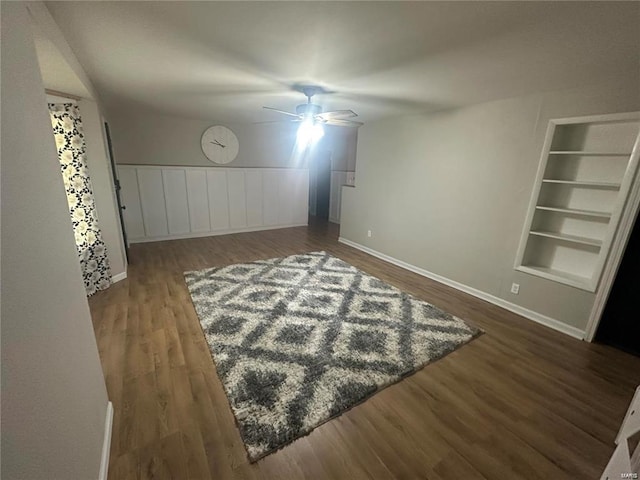 unfurnished room featuring ceiling fan, dark hardwood / wood-style floors, and built in features