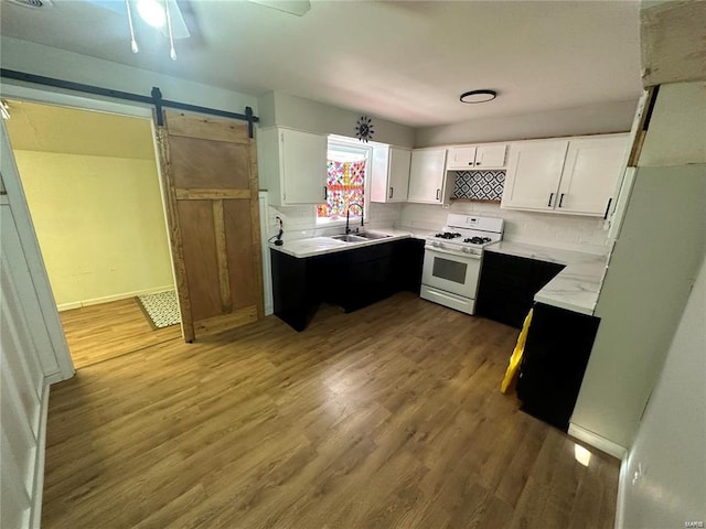 kitchen featuring a barn door, white cabinets, ceiling fan, and gas range gas stove