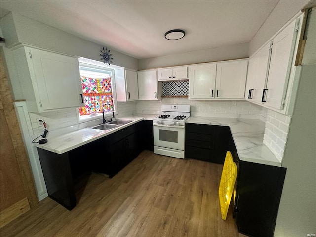 kitchen featuring light hardwood / wood-style floors, white gas stove, sink, white cabinetry, and decorative backsplash