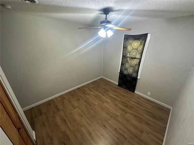 empty room featuring ceiling fan, dark wood-type flooring, and a textured ceiling