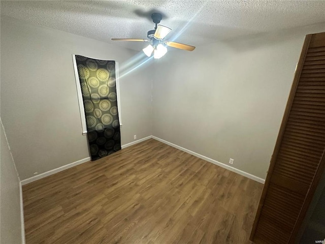 spare room with ceiling fan, a textured ceiling, and wood-type flooring