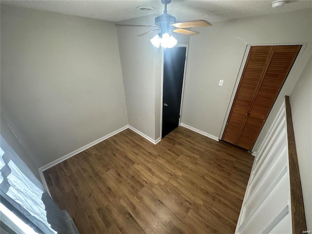 empty room featuring a textured ceiling, ceiling fan, and dark hardwood / wood-style flooring