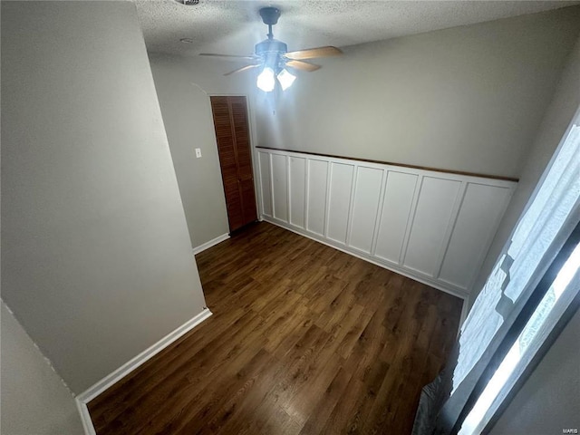 interior space featuring ceiling fan, a textured ceiling, and dark wood-type flooring