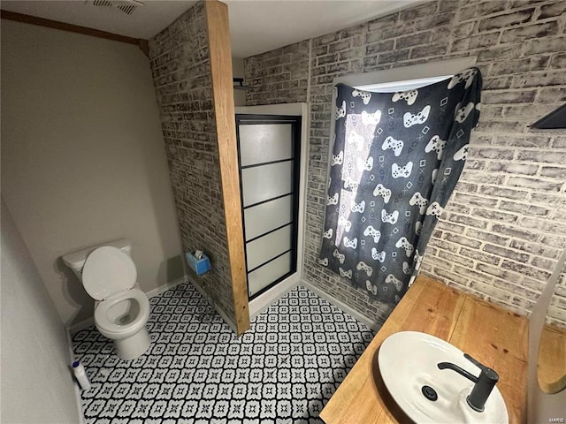 bathroom featuring toilet, brick wall, vanity, and curtained shower