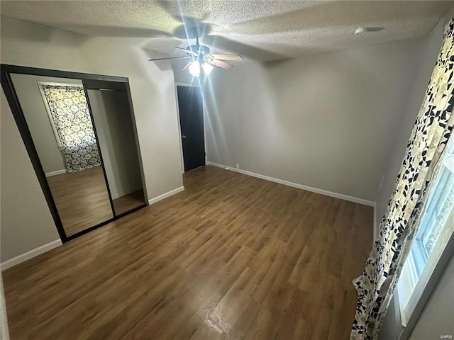 unfurnished bedroom featuring a textured ceiling, dark hardwood / wood-style floors, ceiling fan, and a closet