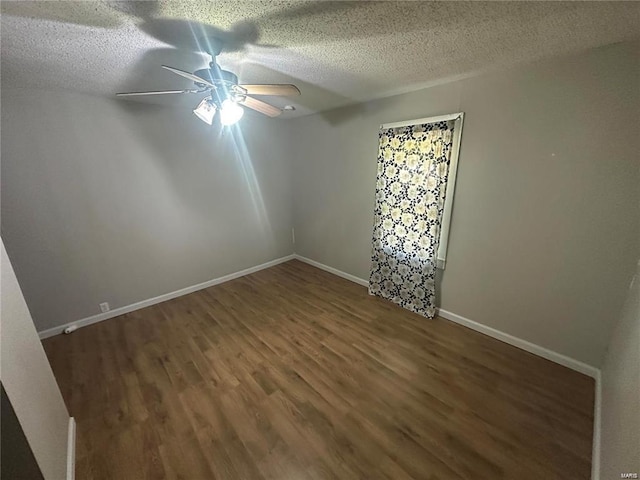 empty room with ceiling fan, dark hardwood / wood-style floors, and a textured ceiling