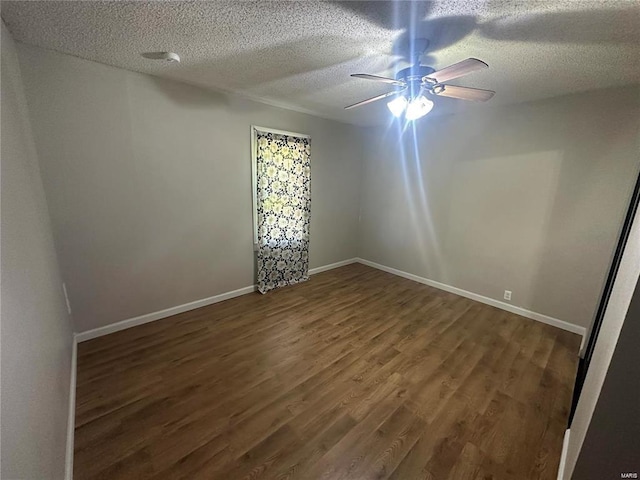 empty room with a textured ceiling, dark hardwood / wood-style floors, and ceiling fan