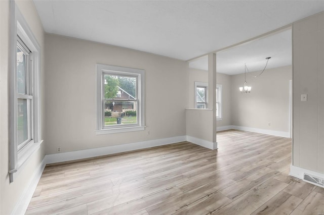 spare room with an inviting chandelier and light hardwood / wood-style floors