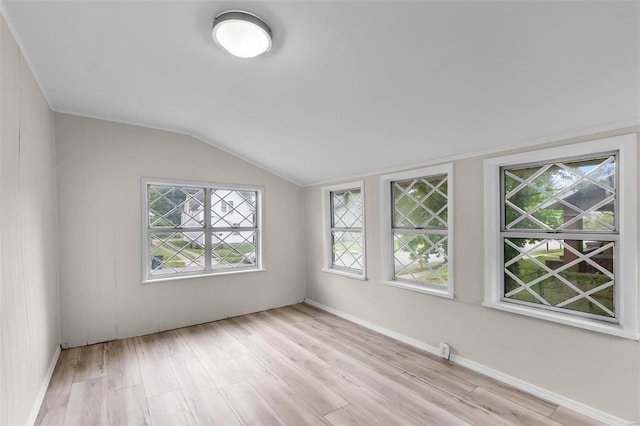 spare room featuring light wood-type flooring and vaulted ceiling