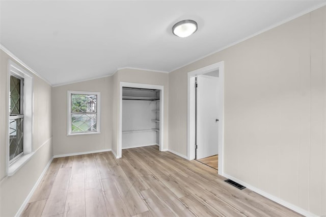 unfurnished bedroom with light wood-type flooring, crown molding, vaulted ceiling, and a closet