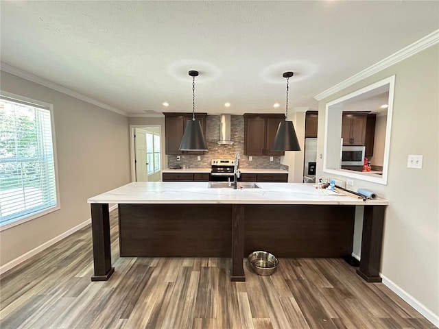 kitchen featuring dark brown cabinets, hanging light fixtures, dark wood-type flooring, and wall chimney range hood