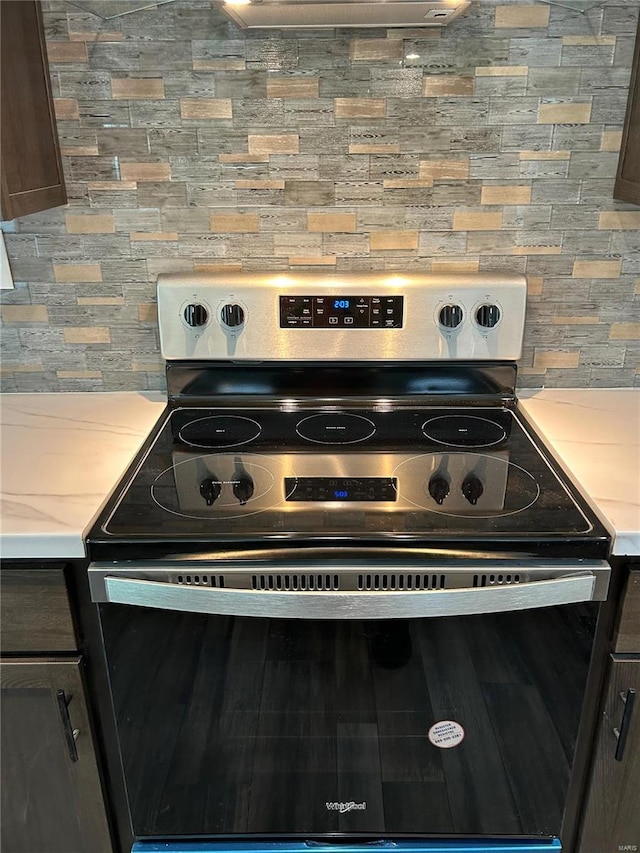 room details featuring dark brown cabinets, backsplash, and stainless steel electric range oven