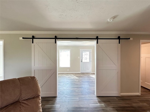 entryway with ornamental molding, a textured ceiling, dark hardwood / wood-style floors, and a barn door