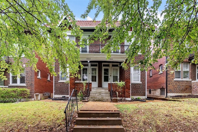 view of front of home with a balcony and a front lawn