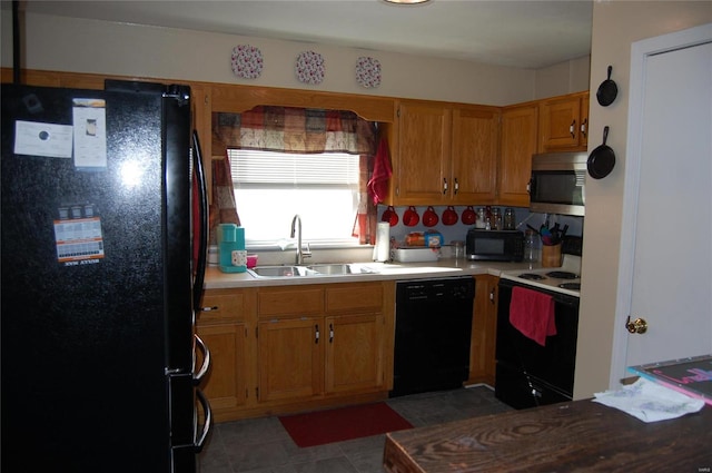 kitchen with sink, dark tile patterned floors, and black appliances