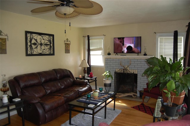 living room with hardwood / wood-style floors, ceiling fan, and a brick fireplace