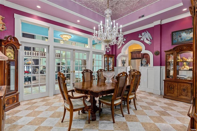 dining room featuring a raised ceiling, ornamental molding, french doors, a chandelier, and a towering ceiling