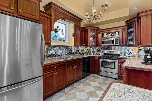 kitchen with pendant lighting, sink, a chandelier, stainless steel appliances, and a tray ceiling