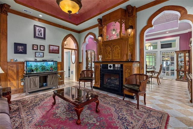 living room with a high ceiling, a tile fireplace, and crown molding