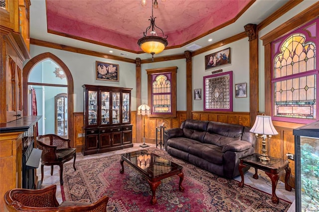 living room featuring a raised ceiling, a healthy amount of sunlight, and crown molding