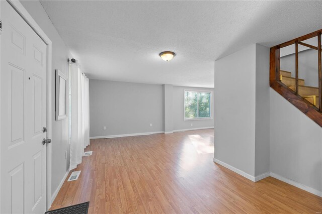 unfurnished room with light hardwood / wood-style floors and a textured ceiling