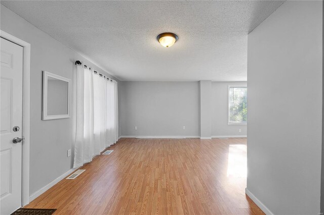 unfurnished room with light hardwood / wood-style flooring and a textured ceiling