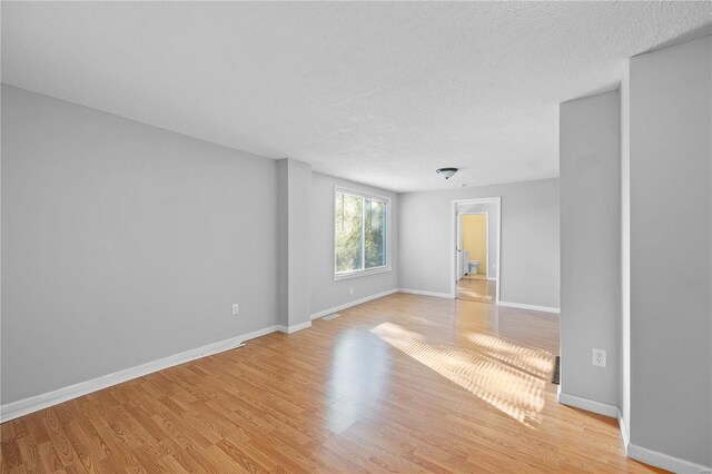 unfurnished room with a textured ceiling and light hardwood / wood-style floors