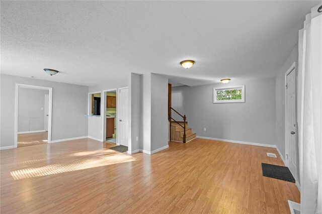 basement featuring a textured ceiling and light hardwood / wood-style flooring