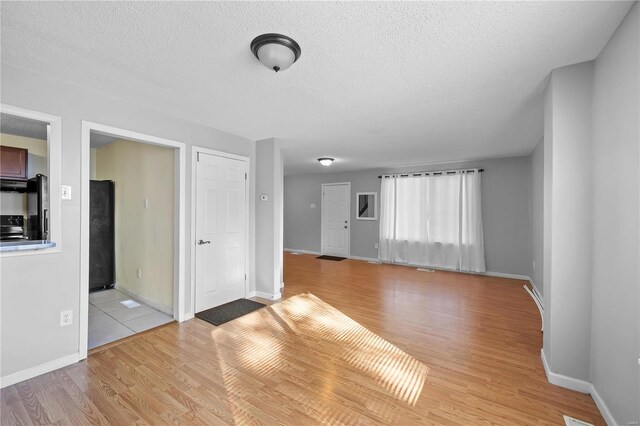 unfurnished living room with a textured ceiling and light hardwood / wood-style floors